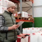 Pekerja gudang mengelola stok persediaan barang dengan tablet digital